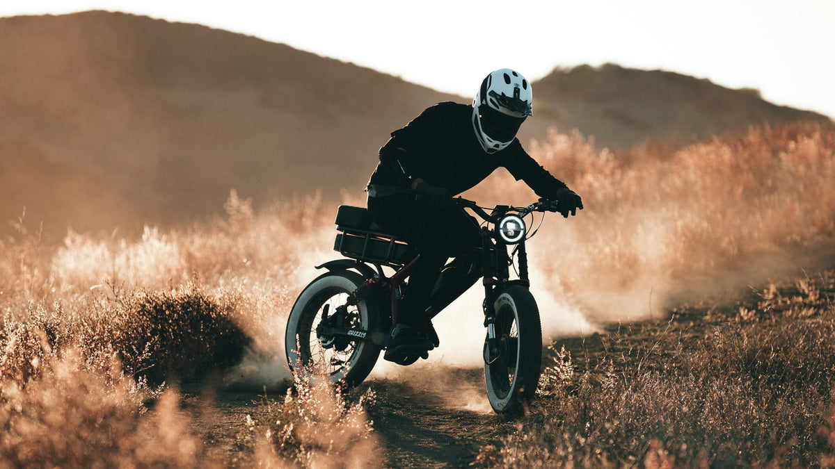 Rider on an electric bike kicking up dust at sunset
